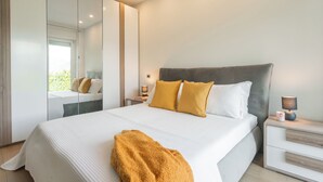 Ein modernes Schlafzimmer mit einem großen Bett, Nachttischen, einem Spiegel und einem Beistelltisch.