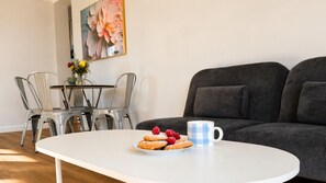 Ein Essbereich mit einem weißen Tisch, einer Auswahl an Gebäck und einer blau karierten Tasse.