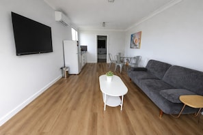 Ein modernes Wohnzimmer mit einem grauen Sofa, einem weißen Couchtisch und einem flachbildfernseher an der Wand.