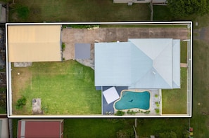 Ein Wohnhaus mit großem Garten, einer freistehenden Garage, einem Schwimmbad und einem gepflegten Rasen.