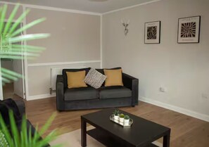 A living room with a sofa, a coffee table, and a radiator. - Renfrew Town Centre, sleeps 6 - Pass the Keys (Renfrew)