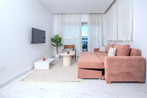 A modern living room with a sofa, TV, and a small table with a plant. - Évasion Marine  (La Marsa)