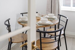 A dining area with round tables and chairs, white plates, and clear glasses. - Central York Apartment with Free Parking & WiFi - Pass the Keys (York)