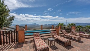 Un espace piscine aménagé sur le toit, avec des chaises longues et une vue sur les montagnes.