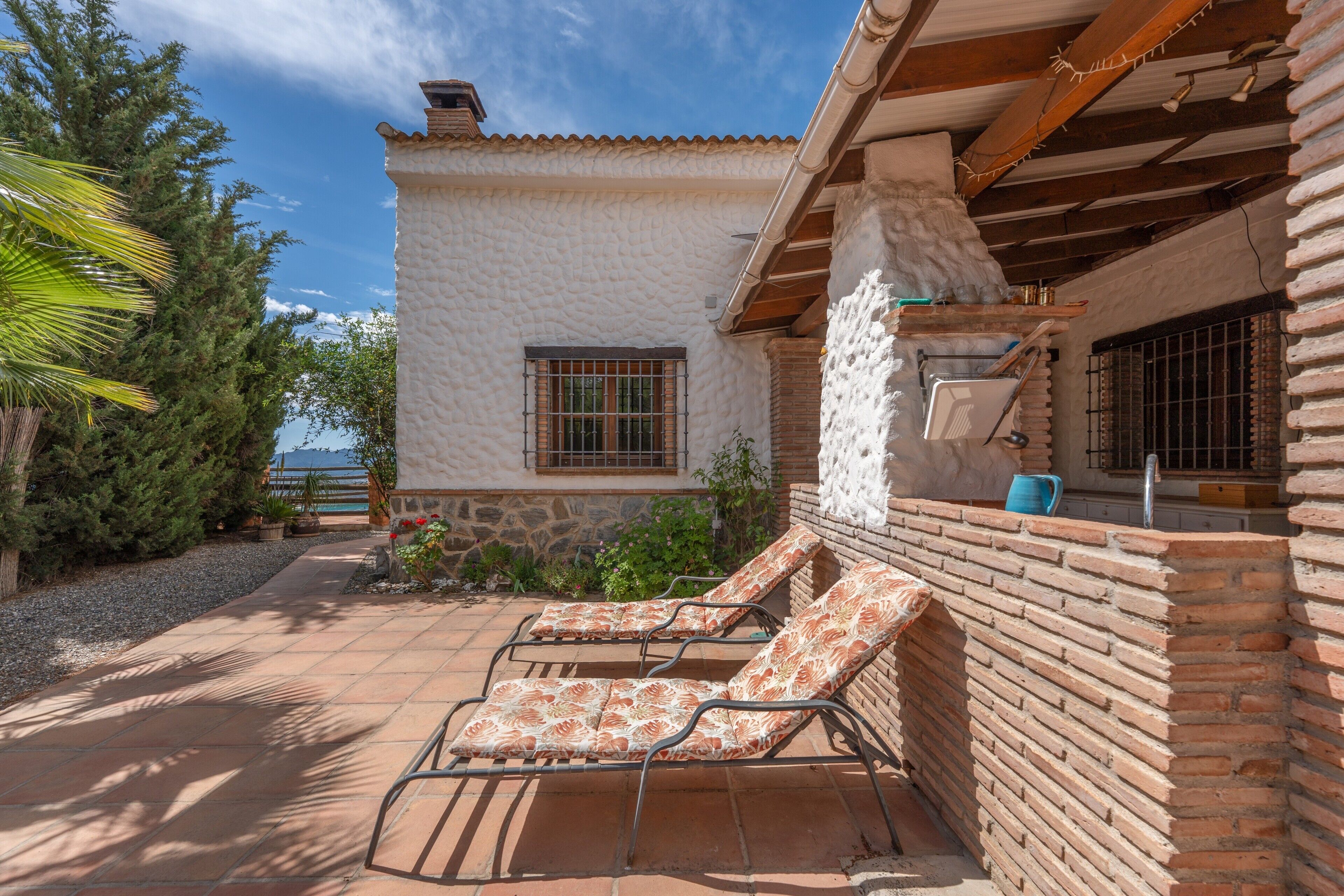 Un patio con dos sillones de descanso, un muro de ladrillo y una ventana con rejas.