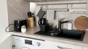 A compact kitchen with a washing machine, a toaster, a coffee maker, and a knife block. - Sunny Stay in Alexanderplatz (Berlin)