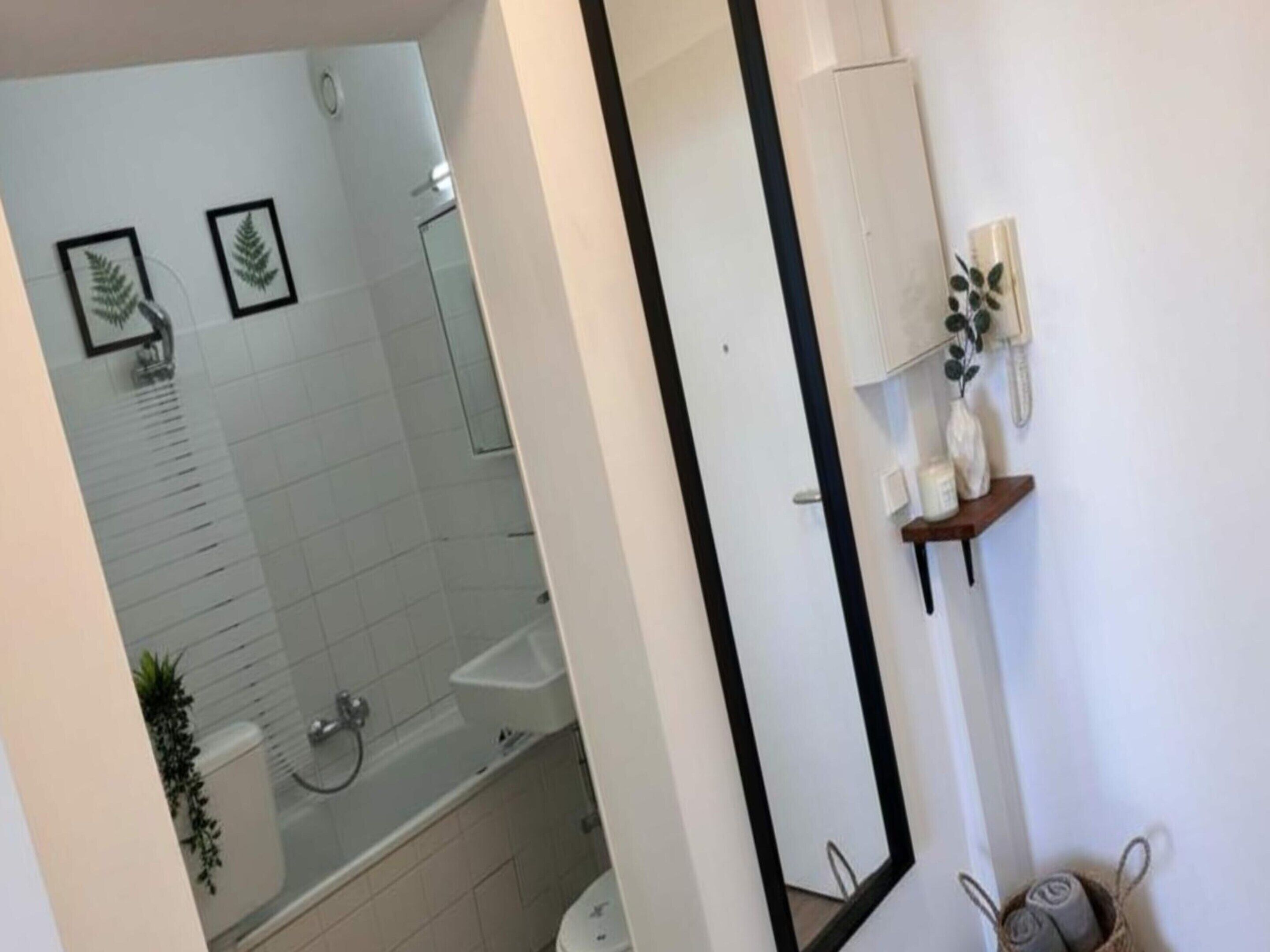 A bathroom with a shower, toilet, and sink. There are framed pictures on the wall and a mirror.