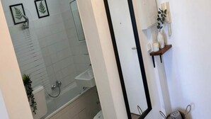 A bathroom with a shower, toilet, and sink. There are framed pictures on the wall and a mirror. - Sunny Stay in Alexanderplatz (Berlin)