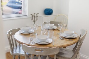 Ein runder Holztisch mit weißen Tellern, klarem Glas und Besteck.