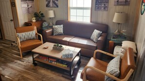 A cozy living room with a brown leather sofa, wooden coffee table, and a bookshelf.