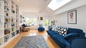 A modern living room with a blue sofa, a bookshelf, and a large skylight. - Stunning South London Home with Rare Garden Oasis - Pass the Keys (London)