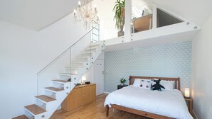 A bedroom with a wooden bed, a white nightstand, a glass staircase, and a ceiling light fixture. - Stunning South London Home with Rare Garden Oasis - Pass the Keys (London)