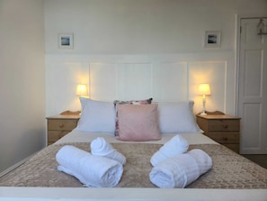 Habitación de hotel con una cama, dos mesitas de noche, dos lámparas y dos cuadros en la pared.