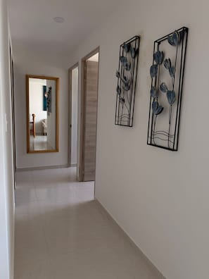 Ein Flur mit einem Spiegel, zwei floralen Wandbildern und einer Holztür.