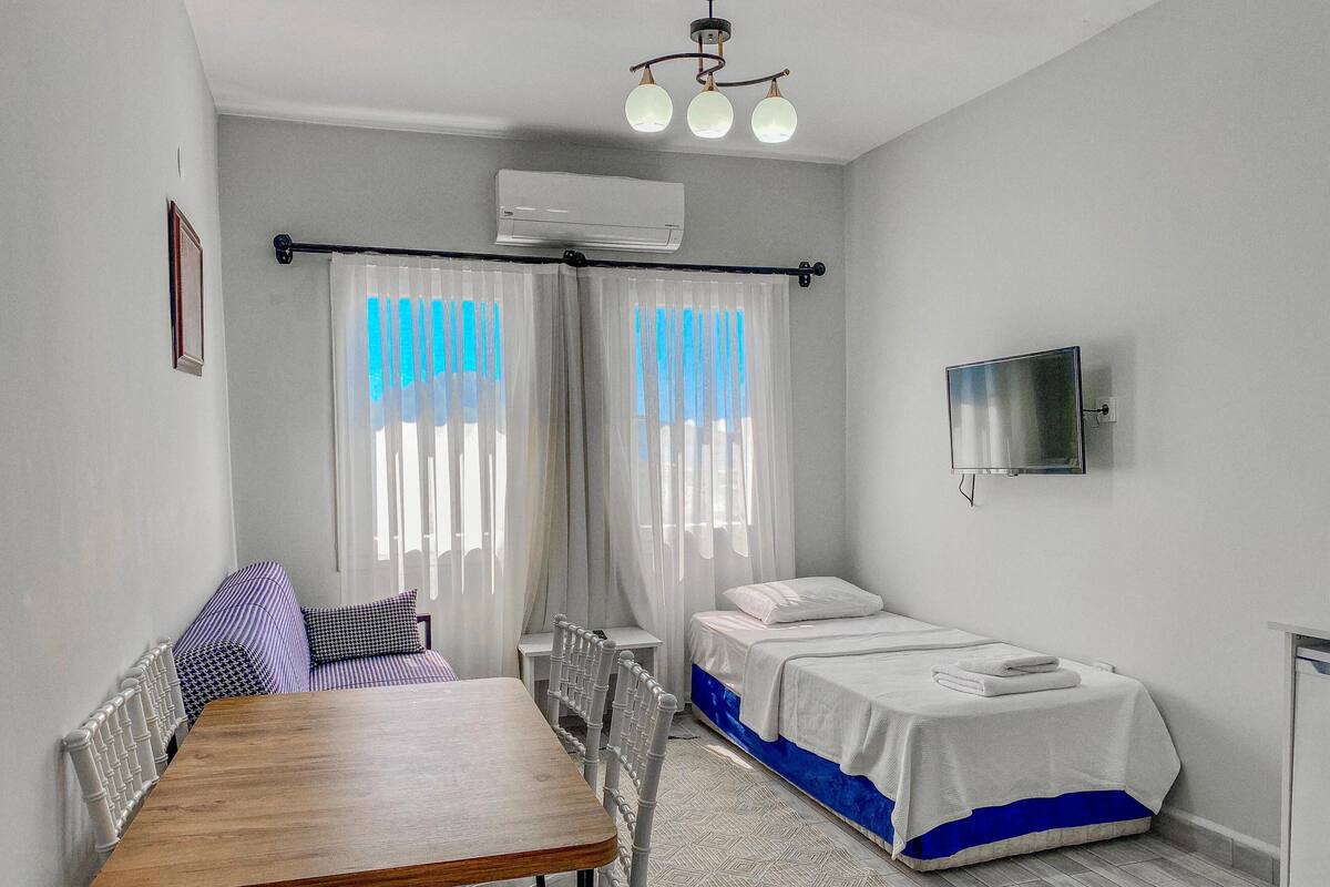 Un dormitorio con cama, televisor, mesa y silla.