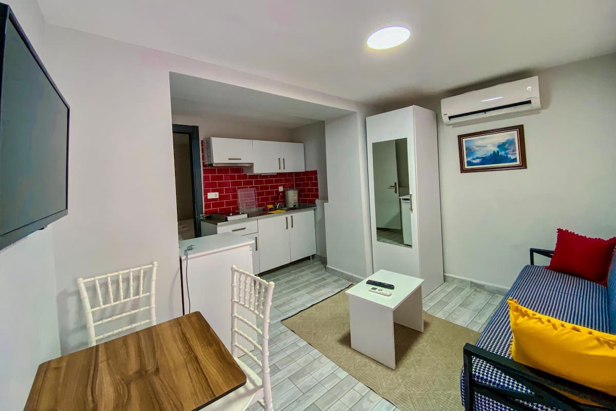 Un espacio habitable compacto con kitchenette, comedor, sofá y cama.