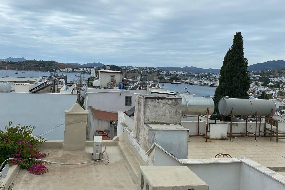 Terraza en la azotea con vista a un cuerpo de agua y colinas lejanas.