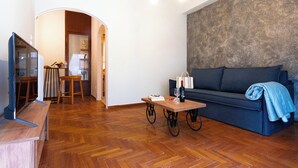 A living room with a sofa, a coffee table, a TV, and a wooden floor. - Acropolis Promenade by Teknys Hosting (Athina)