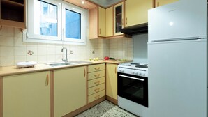 A kitchen with a window, a stove, a sink, and cabinets. - Acropolis Promenade by Teknys Hosting (Athina)