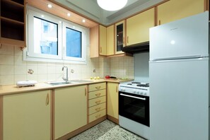 A kitchen with a window, a stove, a sink, and cabinets. - Acropolis Promenade by Teknys Hosting (Athina)