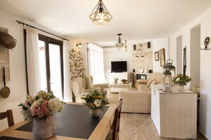 A living room with a fireplace, a television, and a dining area with a table and chairs. - LA POSADA DE LA MUELA (Algodonales)