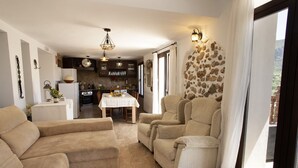 A spacious living area with a dining table, sofas, and a kitchen in the background.