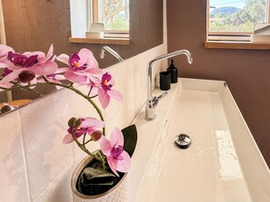 Casa de banho com lavatório branco, espelho e janela.
