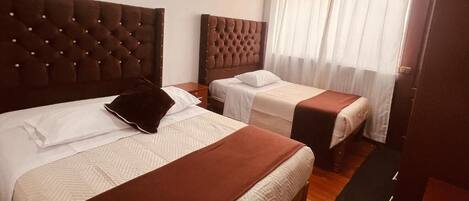 A hotel room with two beds, each with a brown headboard and white bedding.