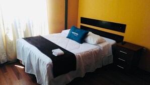 A hotel room with a bed, a nightstand, and a window with curtains. - Hostal Orosheam (Arequipa)