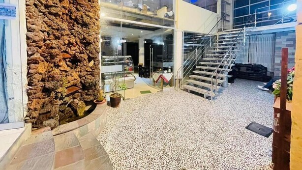 A hotel lobby with a stone wall, a staircase, and a tiled floor. - Hostal Orosheam (Arequipa)