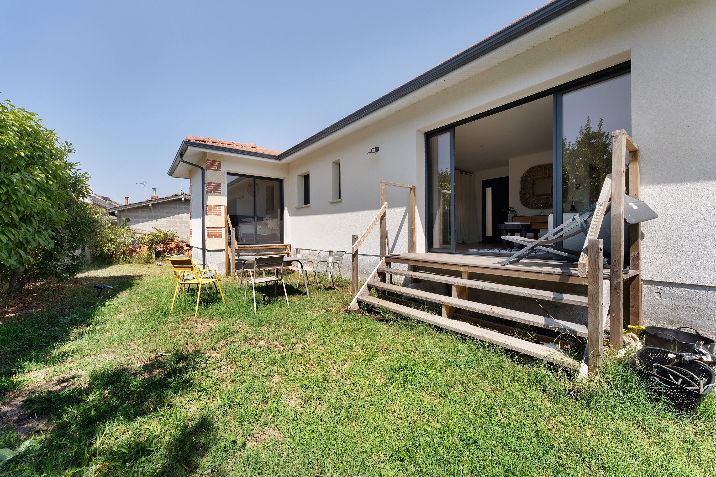 Een woonhuis met een patio, buitenzitplaatsen en een gedeeltelijk afgewerkt terras.