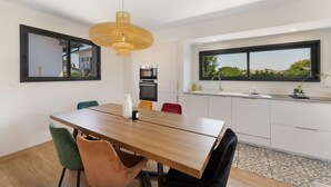 Ett modernt kök med en matplats, med ett träbord, stolar och en hängande lampa.