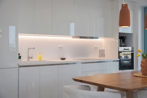 Une cuisine moderne avec des meubles blancs, un évier en acier inoxydable et une table à manger en bois.