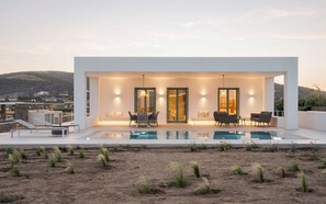 Ein modernes Haus mit Pool, Sitzgelegenheiten im Freien und Blick auf die Landschaft.