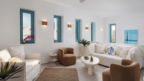 A modern living room with a white sofa, a brown armchair, a round coffee table, and a ceiling fan. - Alkinoe Villa Paros, Bill & John Paros (Paros)