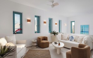 Ein modernes Wohnzimmer mit einem weißen Sofa, einem braunen Sessel, einem runden Couchtisch und einem Deckenventilator.