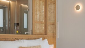 A bedroom with a large bed, a wooden headboard, a mirror, and a nightstand with two decorative vases. - Alkinoe Villa Paros, Bill & John Paros (Paros)