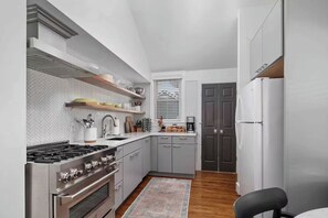 A compact kitchen with a gas stove, oven, and a coffee maker. - Parkview Cottage - Cozy Urban Parkside Stay in Downtown Lexington (Lexington)