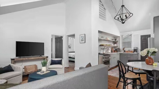 Ein modernes Wohnzimmer mit Flachbildfernseher, einer Couch und einem Essbereich mit Tisch und Stühlen.