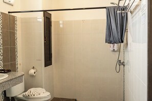 Une salle de bain avec douche, toilettes et lavabo.