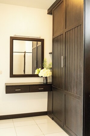 Une salle de bain avec une armoire en bois foncé, un miroir, un lavabo blanc et un vase avec des fleurs.