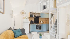 Un apartamento moderno con sala de estar, cocina y una escalera que lleva a un nivel superior.