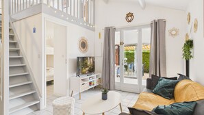 Una sala moderna con una escalera, un televisor y un comedor.