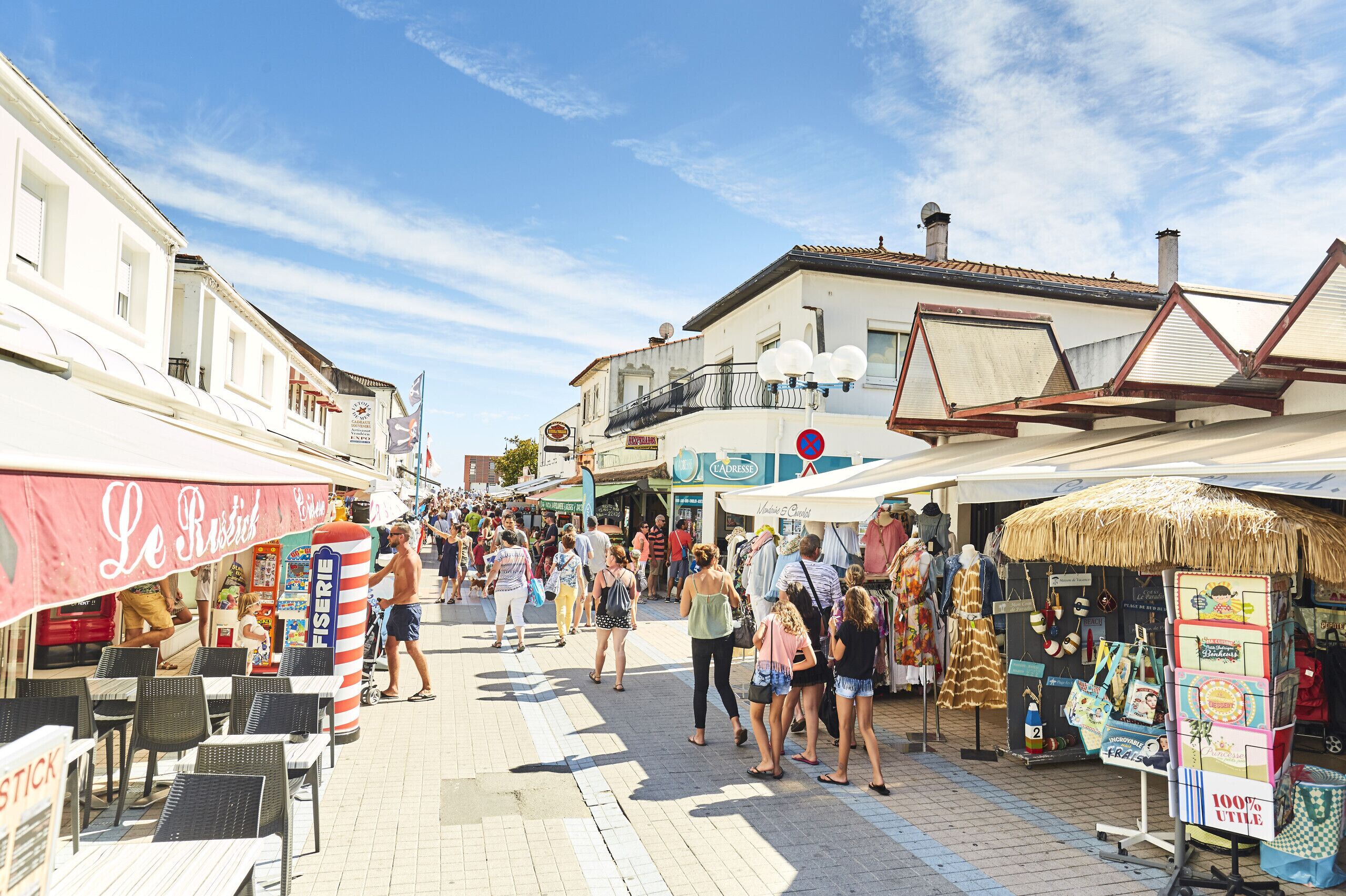Une rue animée, avec des terrasses et de nombreux commerces.