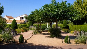 Un jardín cuidado con un sendero de grava que lleva a una casa con techo de tejas.