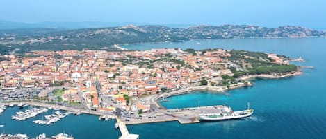 An aerial view of a coastal town with a marina, boats, and a lighthouse.
