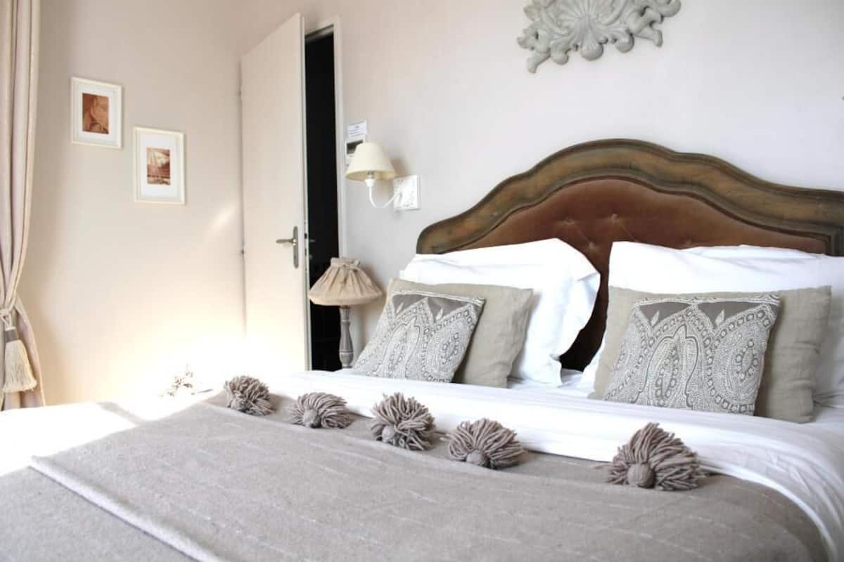 A neatly made bed with patterned pillows, a decorative wall piece, and a lamp.