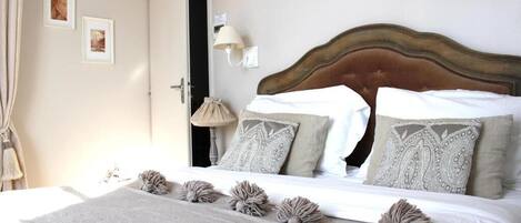 A neatly made bed with patterned pillows, a decorative wall piece, and a lamp.