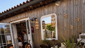 Un groupe de personnes est assis sur des meubles d’extérieur et discute. On aperçoit en arrière-plan un mur en bois et des plantes en pot.