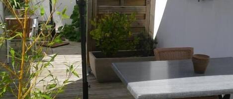 Un patio al aire libre con una mesa, sillas, un cerramiento de madera y plantas en macetas.